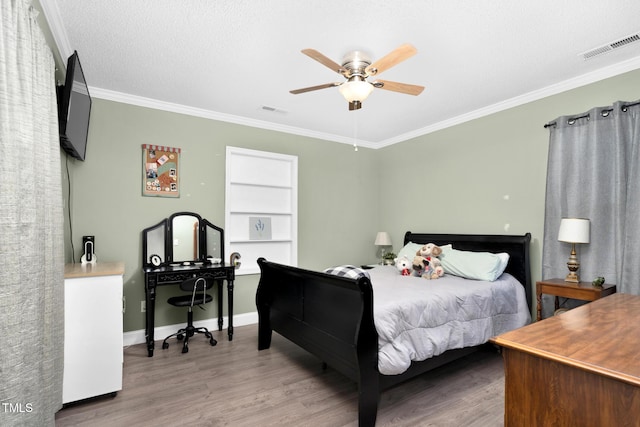 bedroom featuring ornamental molding, wood finished floors, visible vents, and baseboards