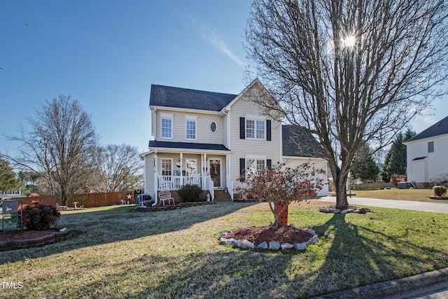 traditional-style home featuring driveway, fence, a porch, and a front yard