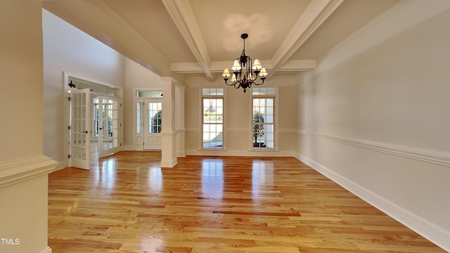 unfurnished dining area featuring decorative columns, an inviting chandelier, light hardwood / wood-style floors, and beamed ceiling