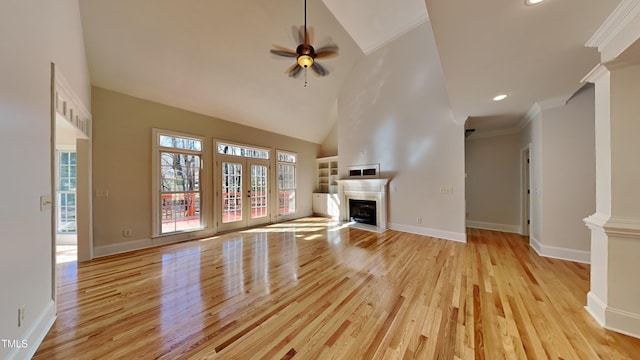 unfurnished living room with high vaulted ceiling, ceiling fan, crown molding, light wood-type flooring, and french doors