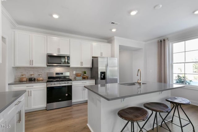 kitchen featuring stainless steel appliances, sink, a center island with sink, and white cabinets