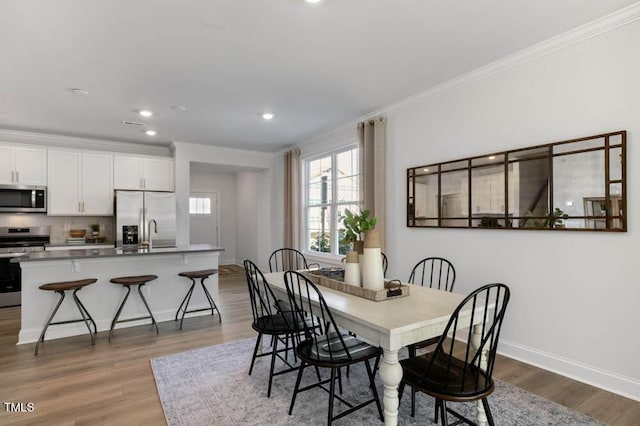 dining space featuring crown molding and light hardwood / wood-style floors