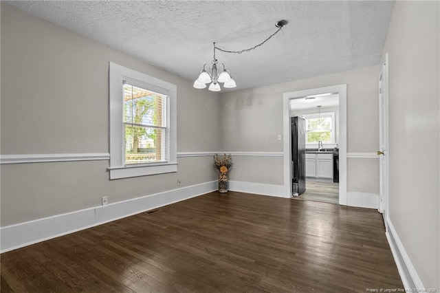 spare room featuring dark hardwood / wood-style floors, sink, a textured ceiling, and a chandelier