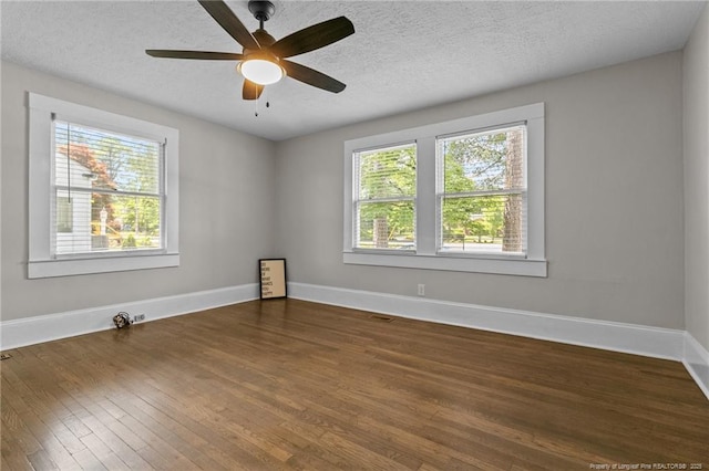 empty room with dark wood-type flooring, a healthy amount of sunlight, and a textured ceiling