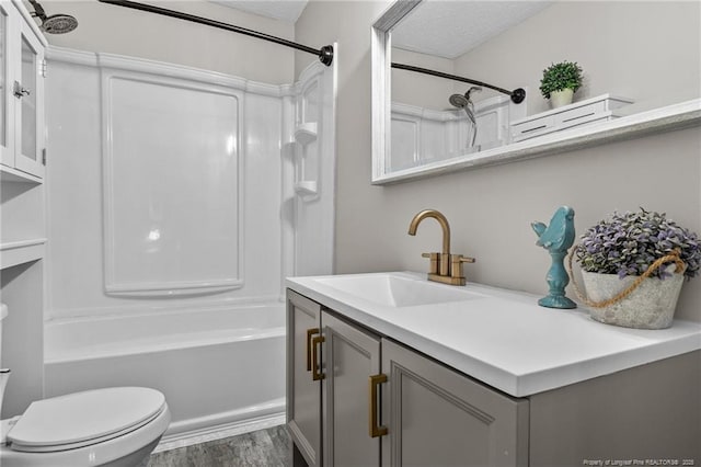 full bathroom featuring toilet, bathing tub / shower combination, wood-type flooring, a textured ceiling, and vanity