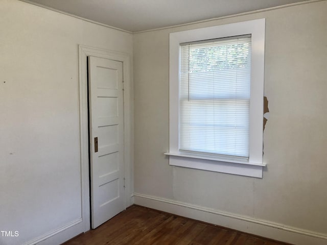 spare room featuring dark wood-style flooring and baseboards