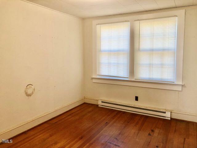 spare room featuring dark wood-style floors, a baseboard radiator, and baseboards