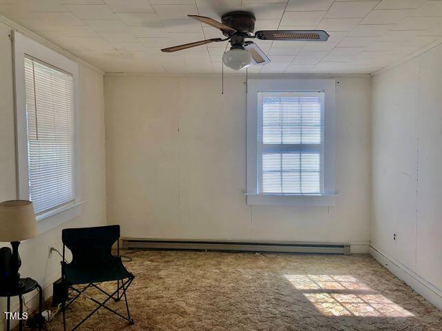 unfurnished room with carpet floors, ceiling fan, and baseboard heating