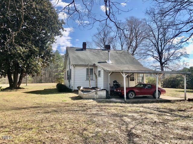 view of front of home with a chimney, a carport, and a front yard