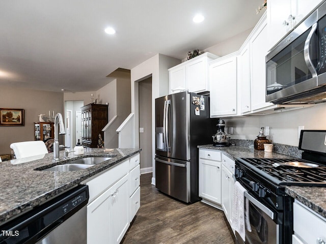 kitchen with sink, dark stone countertops, stainless steel appliances, dark hardwood / wood-style floors, and white cabinets