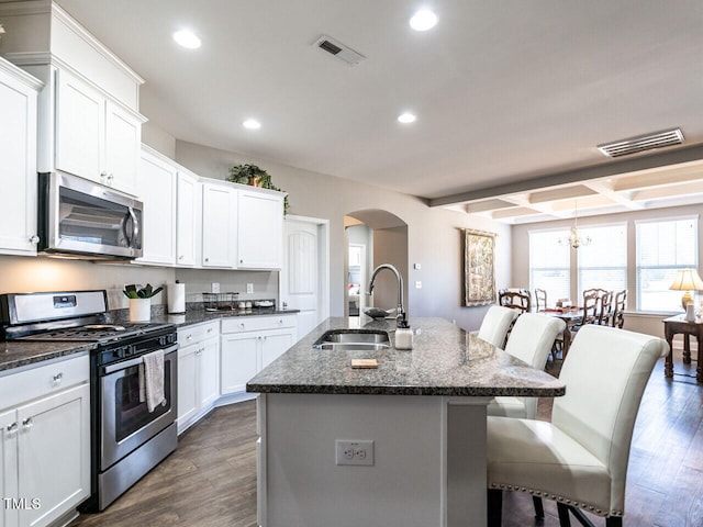 kitchen with appliances with stainless steel finishes, sink, a kitchen breakfast bar, dark wood-type flooring, and a center island with sink