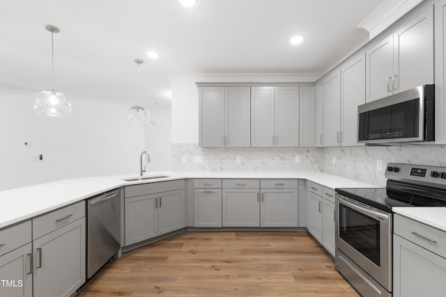 kitchen featuring appliances with stainless steel finishes, decorative light fixtures, gray cabinets, and sink