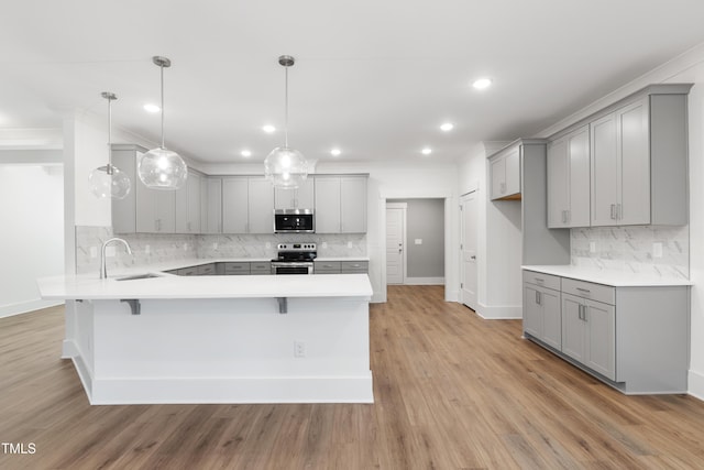 kitchen featuring sink, appliances with stainless steel finishes, gray cabinetry, hanging light fixtures, and kitchen peninsula