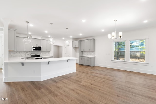 kitchen with stainless steel appliances, hanging light fixtures, and gray cabinetry