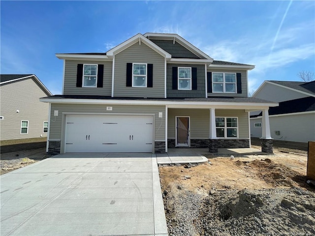 craftsman inspired home featuring an attached garage, covered porch, stone siding, and driveway