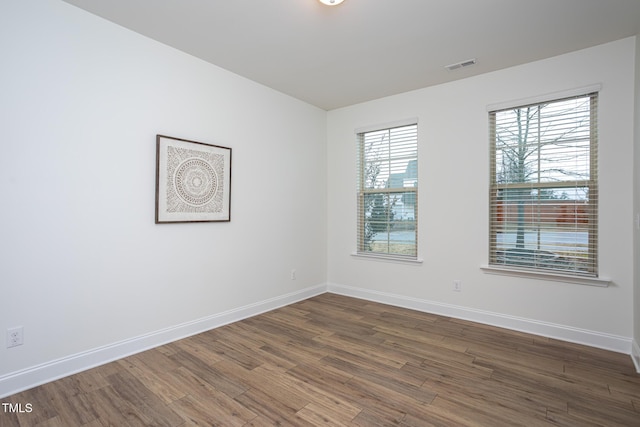 empty room featuring plenty of natural light and dark wood-type flooring