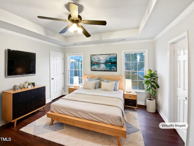 bedroom featuring dark hardwood / wood-style flooring, a tray ceiling, ornamental molding, and ceiling fan