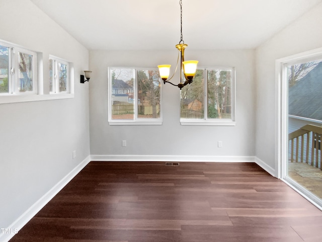 unfurnished dining area featuring an inviting chandelier, plenty of natural light, and dark hardwood / wood-style floors