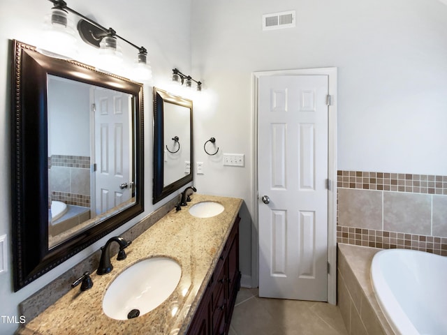 bathroom with vanity, tile patterned flooring, and tiled tub