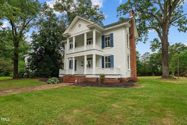 greek revival house with a balcony, covered porch, and a front lawn