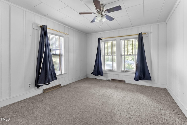 spare room with crown molding, a wealth of natural light, ceiling fan, and carpet