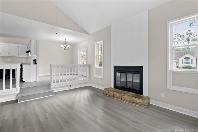 unfurnished living room featuring an inviting chandelier, a fireplace, wood-type flooring, and vaulted ceiling