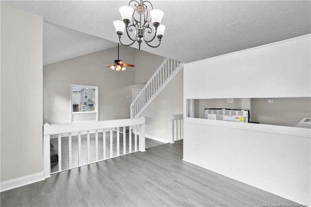 living room with vaulted ceiling, ceiling fan with notable chandelier, and hardwood / wood-style floors