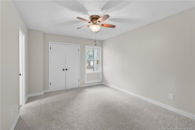 unfurnished bedroom with ceiling fan, carpet flooring, a closet, and a textured ceiling