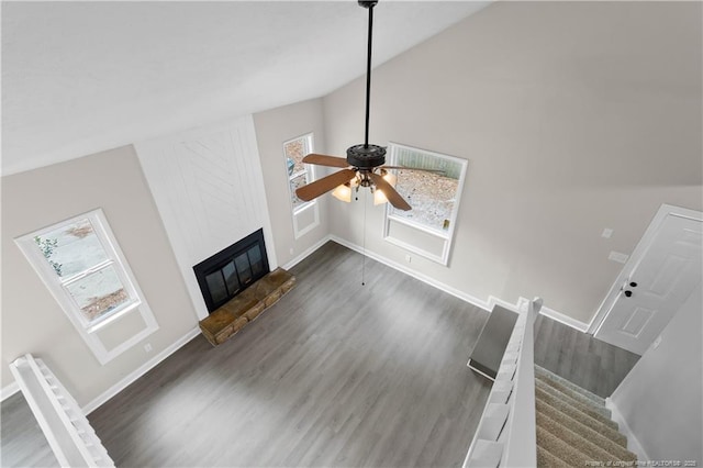 unfurnished living room featuring vaulted ceiling, ceiling fan, a fireplace, and dark hardwood / wood-style flooring