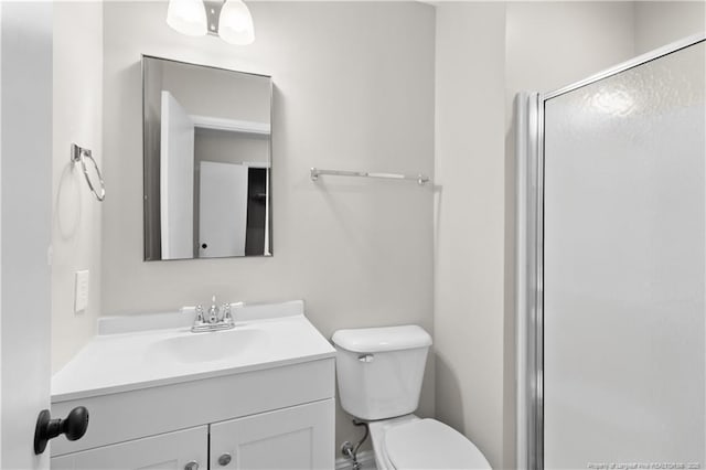 bathroom featuring vanity, a shower with shower door, and toilet