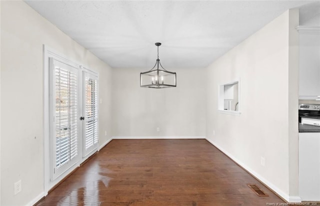 unfurnished dining area featuring dark wood-type flooring and a chandelier