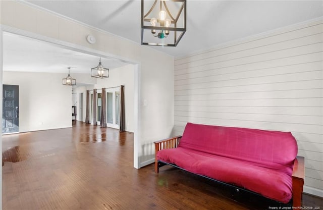 sitting room with dark wood-type flooring, crown molding, and a chandelier