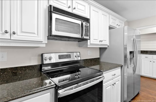 kitchen featuring stainless steel appliances, dark stone countertops, and white cabinets