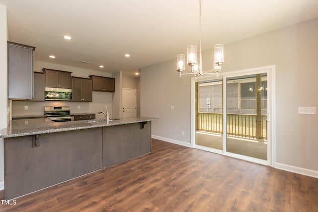 kitchen featuring appliances with stainless steel finishes, decorative light fixtures, sink, dark hardwood / wood-style flooring, and light stone counters