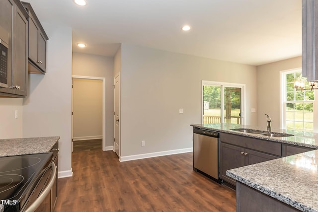 kitchen with appliances with stainless steel finishes, light stone countertops, sink, and dark brown cabinets