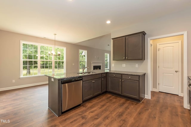 kitchen with dark hardwood / wood-style floors, stainless steel dishwasher, decorative light fixtures, and light stone countertops