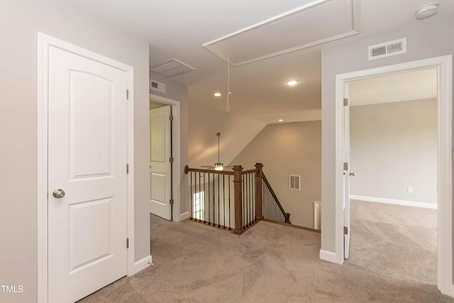 corridor with lofted ceiling and light colored carpet