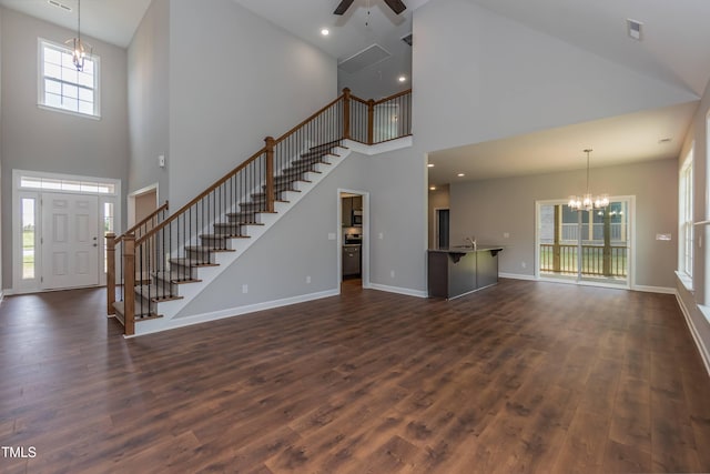 unfurnished living room featuring dark wood-type flooring and ceiling fan with notable chandelier