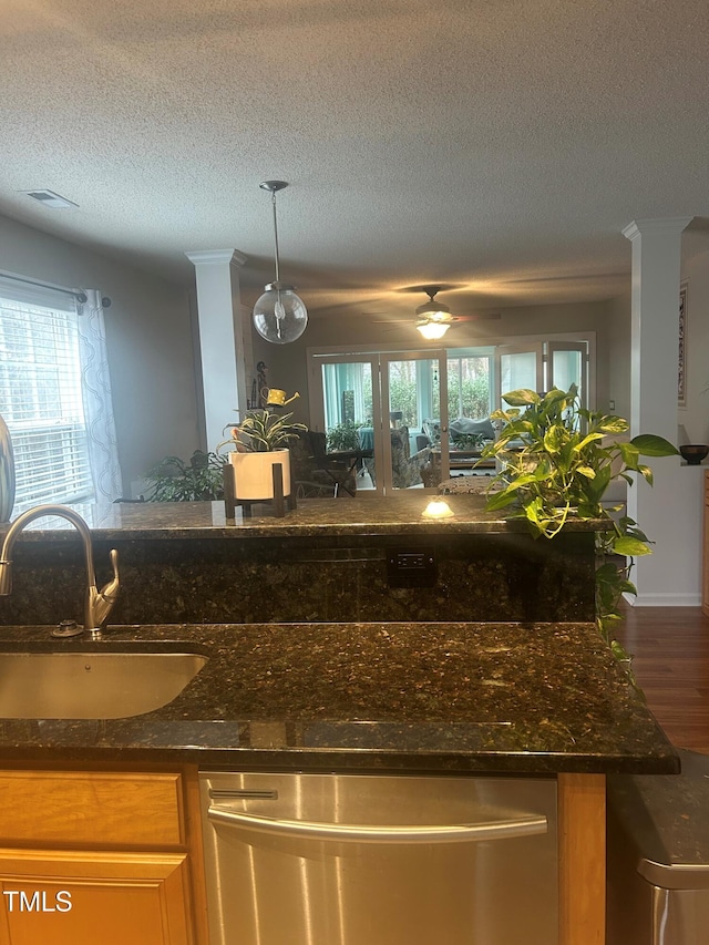 kitchen with dishwasher, sink, hanging light fixtures, and dark stone countertops