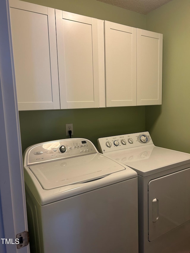 laundry room featuring cabinets, washing machine and clothes dryer, and a textured ceiling