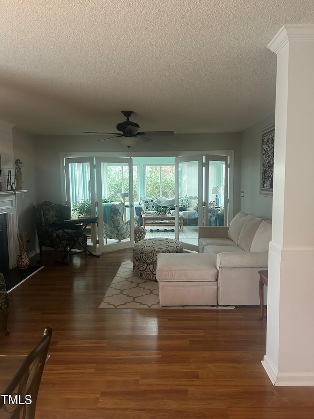 living room featuring ceiling fan, dark hardwood / wood-style floors, and a textured ceiling