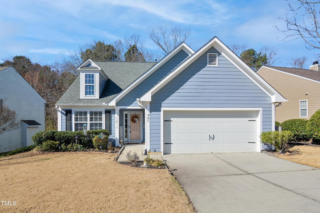 view of front of home with driveway, a shingled roof, an attached garage, and a front yard