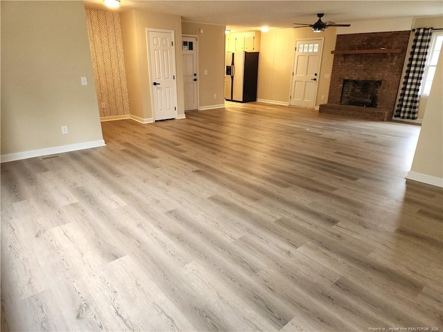 unfurnished living room with hardwood / wood-style flooring, ceiling fan, and a fireplace