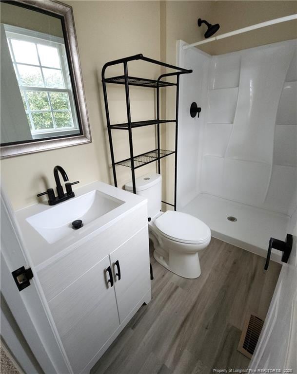 bathroom featuring vanity, hardwood / wood-style flooring, toilet, and walk in shower