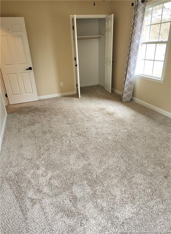 unfurnished bedroom featuring light colored carpet and a closet