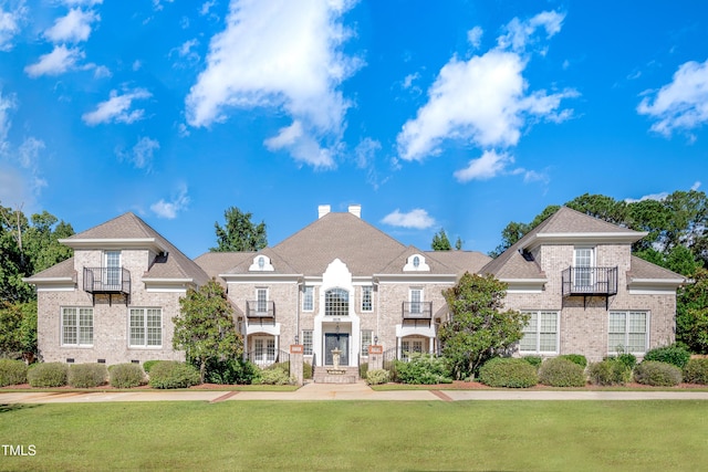 view of front of property with a balcony and a front lawn