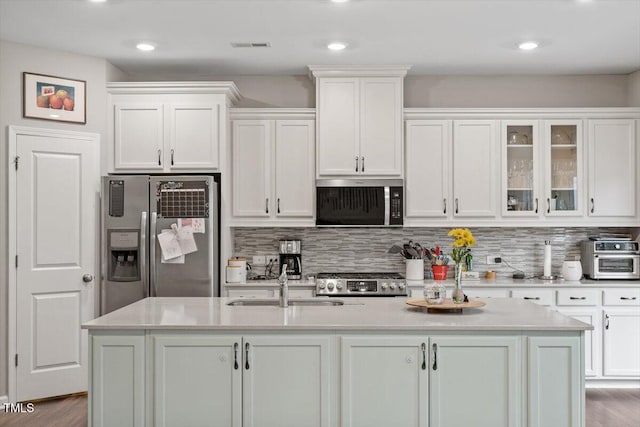 kitchen with white cabinetry, a center island with sink, tasteful backsplash, and appliances with stainless steel finishes