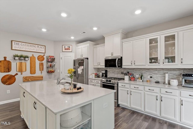 kitchen featuring tasteful backsplash, white cabinetry, dark hardwood / wood-style flooring, a kitchen island with sink, and stainless steel appliances