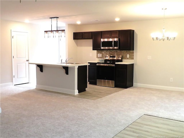 kitchen with decorative light fixtures, light colored carpet, and appliances with stainless steel finishes