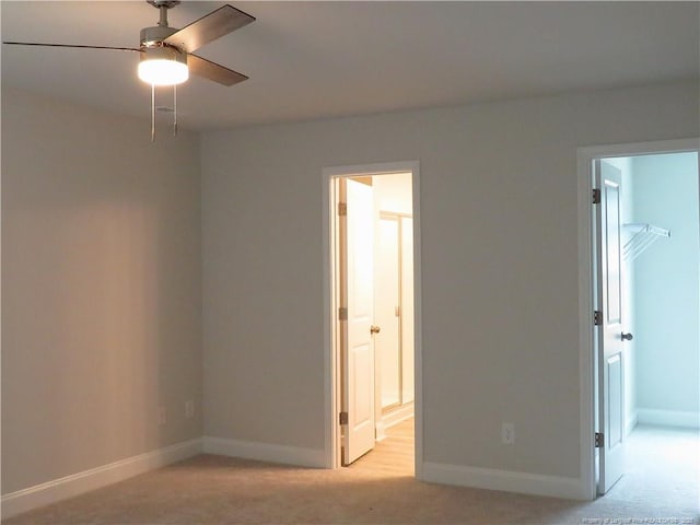 unfurnished bedroom featuring a spacious closet, light carpet, ensuite bath, and a closet